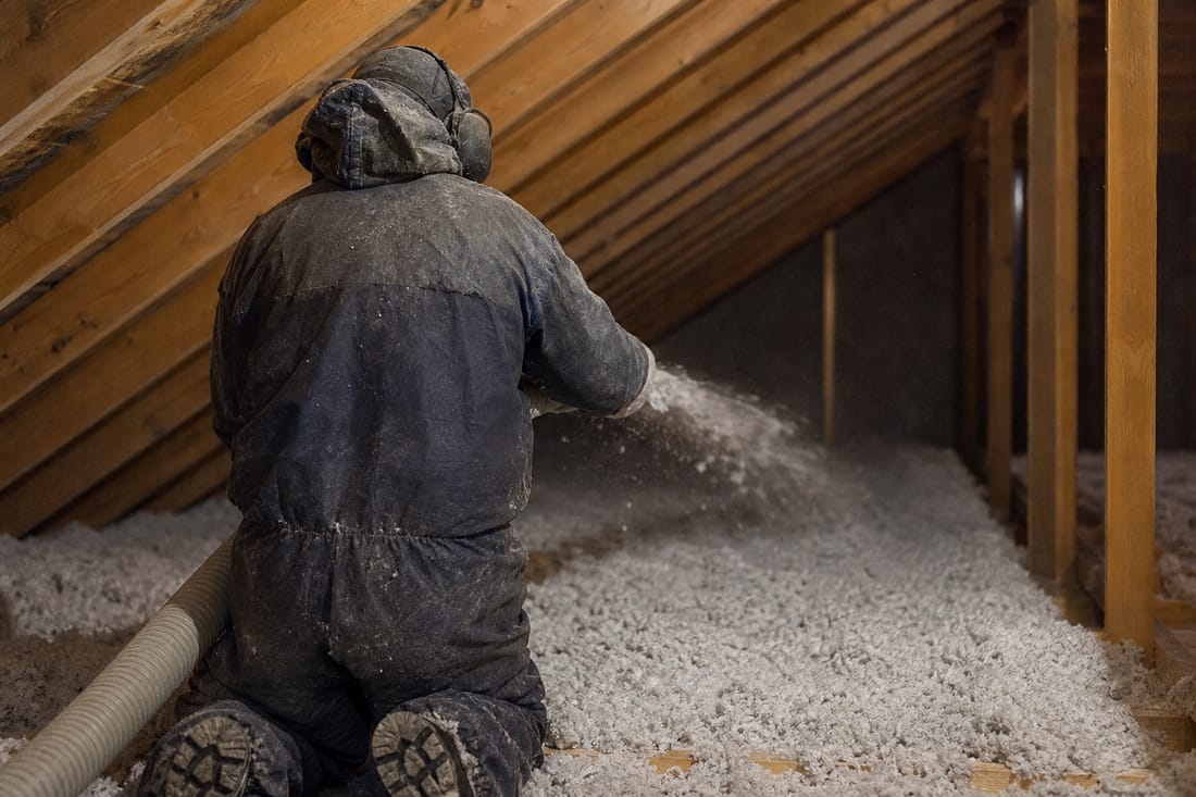Beispiel: Handwerker von hinten beim Einblasen von Dämmstoff